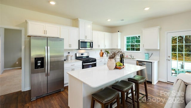 kitchen with stainless steel appliances, a center island, white cabinets, and a breakfast bar