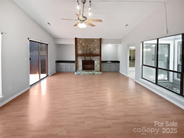 unfurnished living room with ceiling fan, a healthy amount of sunlight, a fireplace, and light hardwood / wood-style flooring