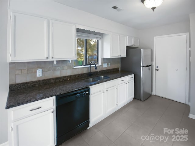 kitchen with stainless steel refrigerator, white cabinetry, dishwasher, sink, and dark stone countertops