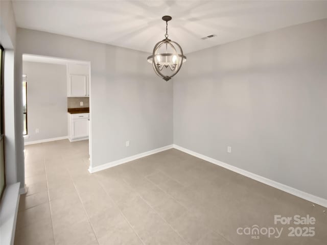 tiled spare room with a notable chandelier