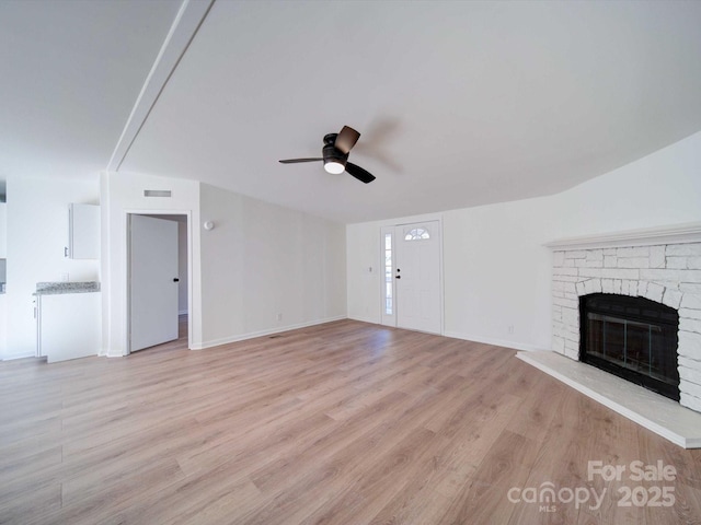 unfurnished living room with ceiling fan, a fireplace, and light wood-type flooring