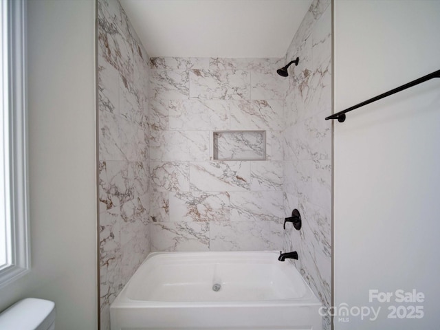 bathroom featuring tiled shower / bath and toilet