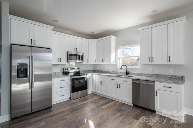 kitchen with sink, stainless steel appliances, dark hardwood / wood-style floors, light stone counters, and white cabinets