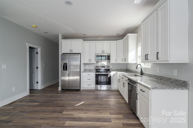 kitchen featuring white cabinetry, sink, stainless steel appliances, light stone countertops, and dark wood-type flooring