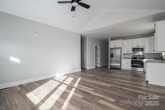 kitchen with sink, stone counters, stainless steel appliances, white cabinets, and dark hardwood / wood-style flooring