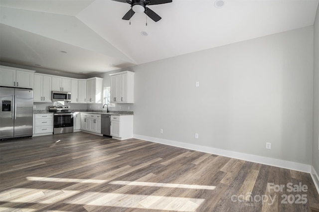 kitchen featuring appliances with stainless steel finishes, white cabinetry, lofted ceiling, sink, and wood-type flooring