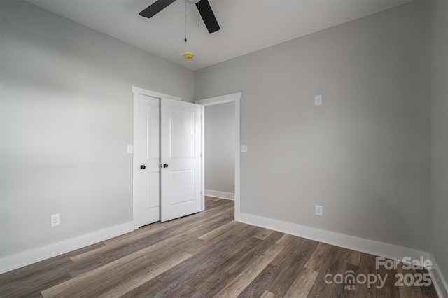 unfurnished bedroom featuring dark wood-type flooring, ceiling fan, and a closet