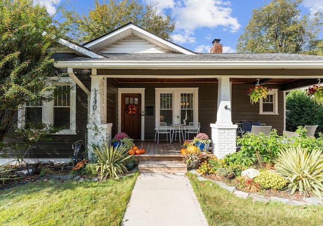 view of front of house with covered porch, a chimney, and roof with shingles