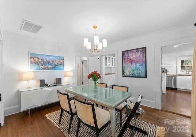 dining space with ornamental molding, dark wood finished floors, visible vents, and a notable chandelier