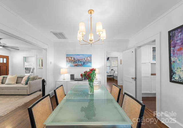 dining area with crown molding, visible vents, dark wood finished floors, and ceiling fan with notable chandelier