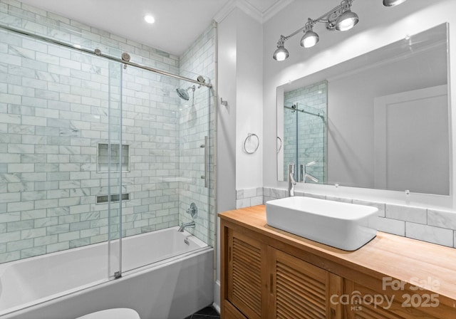 bathroom featuring enclosed tub / shower combo, vanity, toilet, and crown molding