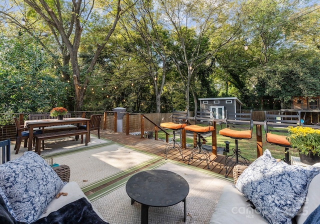 view of patio / terrace with a wooden deck, fence, outdoor dining area, and an outdoor structure