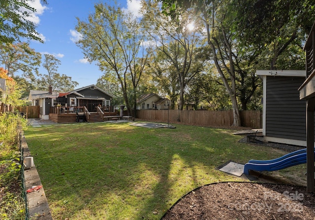 view of yard with a patio area, a fenced backyard, a deck, and a playground