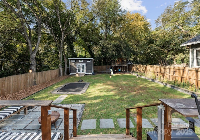 view of yard featuring a fenced backyard, a storage unit, and an outbuilding