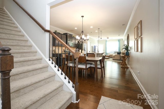 stairs with hardwood / wood-style flooring, ornamental molding, sink, and an inviting chandelier