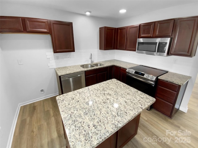 kitchen featuring light stone counters, sink, stainless steel appliances, and light wood-type flooring