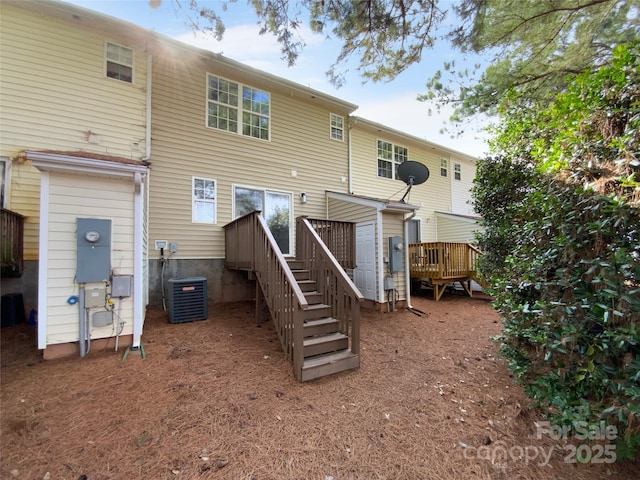 rear view of property featuring a wooden deck and central AC unit