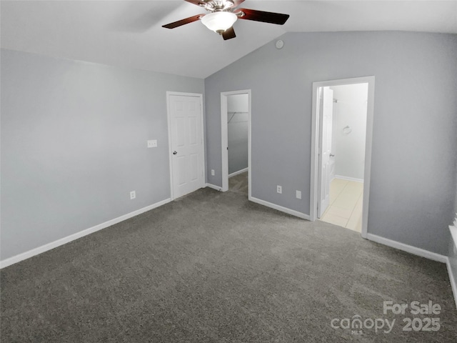 unfurnished bedroom with lofted ceiling, ensuite bathroom, carpet floors, a walk in closet, and a closet