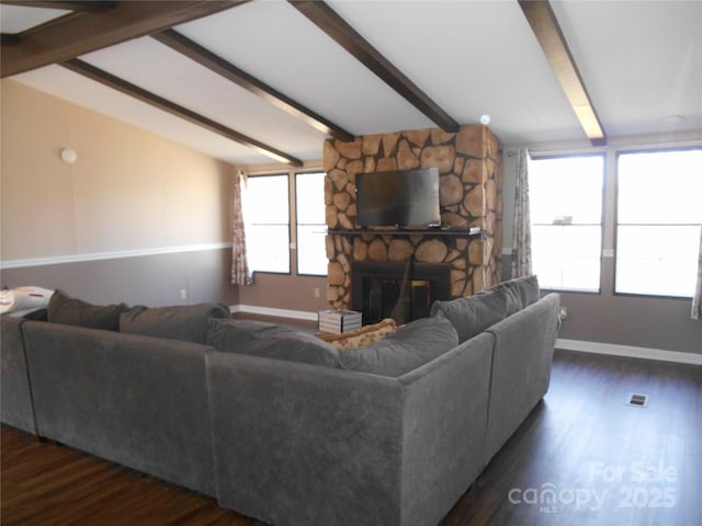 living room with a stone fireplace, dark hardwood / wood-style floors, and vaulted ceiling with beams