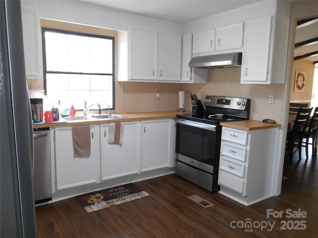 kitchen with dark wood-type flooring, sink, ventilation hood, stainless steel appliances, and white cabinets