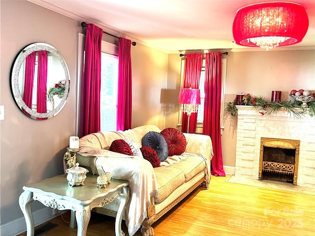 bedroom with hardwood / wood-style flooring, crown molding, and a stone fireplace