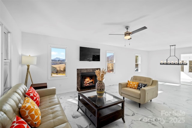 living room featuring ceiling fan with notable chandelier and a high end fireplace