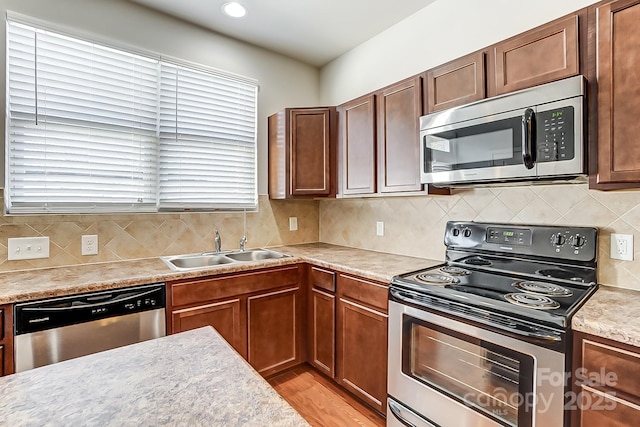 kitchen featuring tasteful backsplash, sink, stainless steel appliances, and light hardwood / wood-style floors