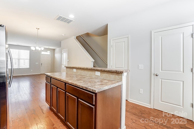 kitchen with stainless steel refrigerator, a notable chandelier, decorative light fixtures, and light wood-type flooring