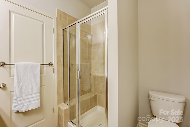 bathroom featuring toilet and a shower with shower door