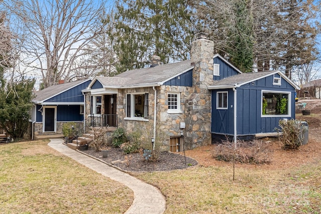 view of front of property with board and batten siding, roof with shingles, a chimney, and a front lawn