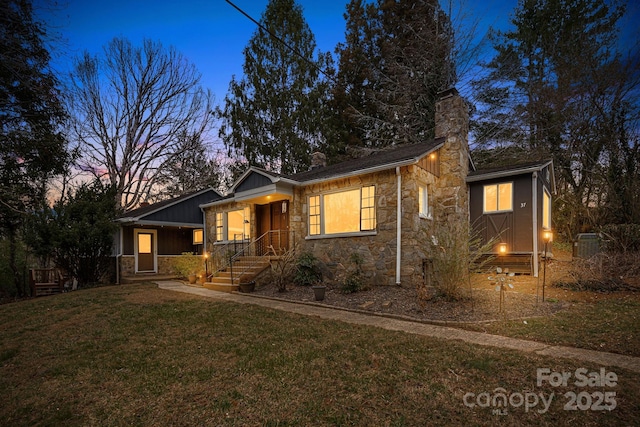 view of front of house with stone siding, a chimney, covered porch, and a yard