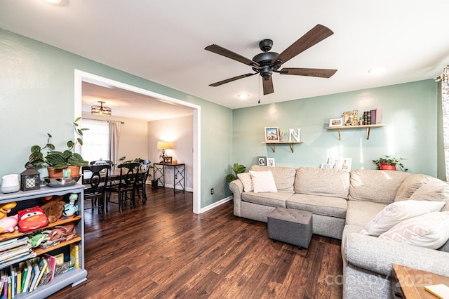 living area featuring a ceiling fan, baseboards, and wood finished floors