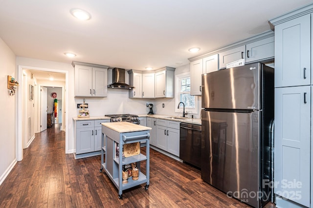 kitchen with dark wood-style floors, stainless steel appliances, wall chimney range hood, and a sink