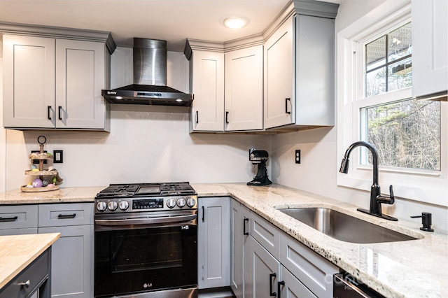 kitchen with gray cabinetry, a sink, wall chimney exhaust hood, and gas range