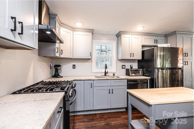 kitchen featuring wall chimney range hood, appliances with stainless steel finishes, gray cabinets, and a sink