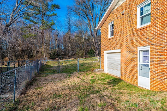 view of yard with driveway, an attached garage, and fence