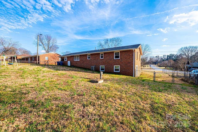 back of property featuring a fenced backyard, a gate, a lawn, and brick siding