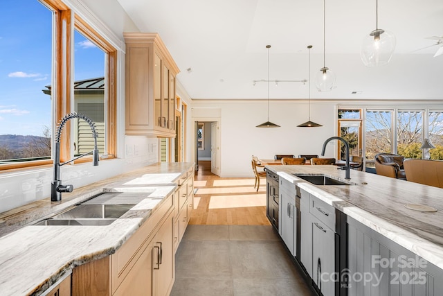 kitchen featuring light stone counters, sink, and hanging light fixtures