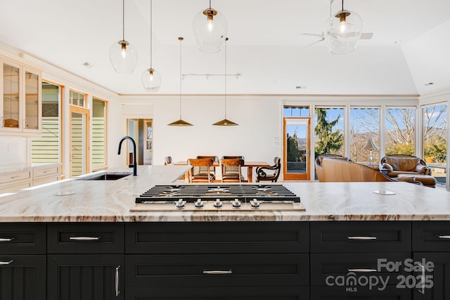 kitchen featuring hanging light fixtures, stainless steel gas cooktop, sink, and a kitchen island with sink