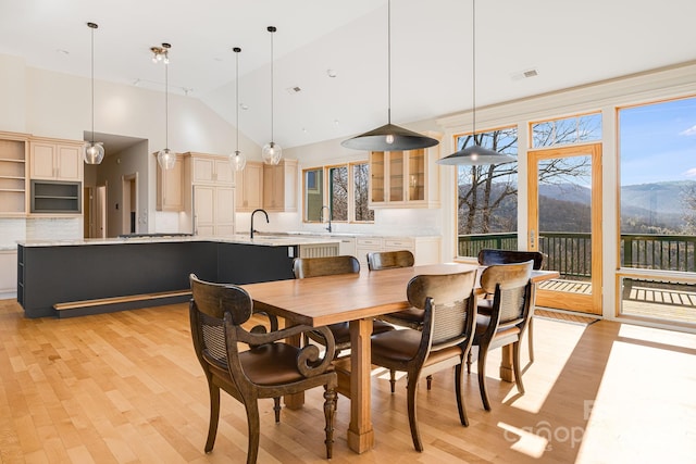 dining area with a mountain view, high vaulted ceiling, sink, and light wood-type flooring