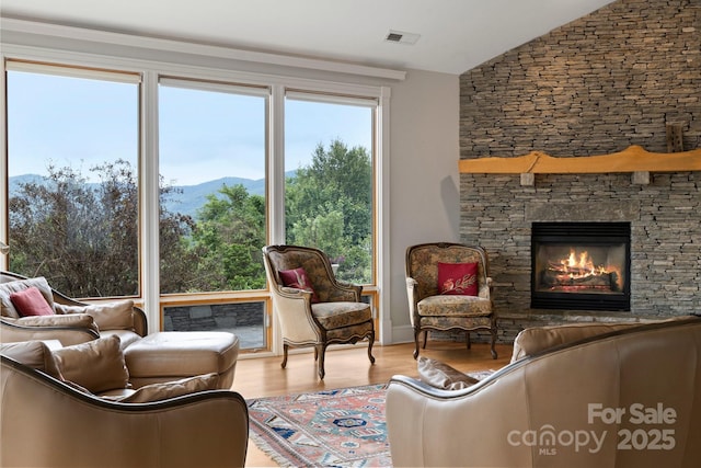 interior space with vaulted ceiling, a fireplace, a mountain view, and light hardwood / wood-style floors