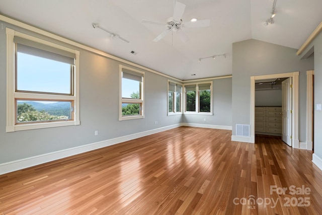 unfurnished bedroom with hardwood / wood-style flooring, vaulted ceiling, a closet, and track lighting