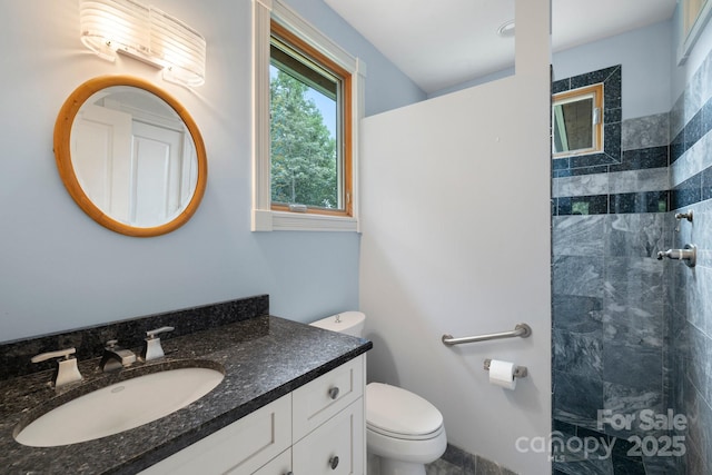 bathroom with tiled shower, vanity, and toilet