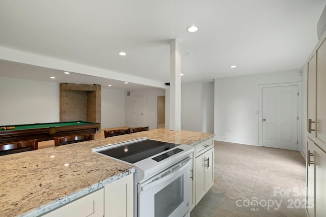 kitchen featuring light stone counters, white range with electric cooktop, pool table, and white cabinets