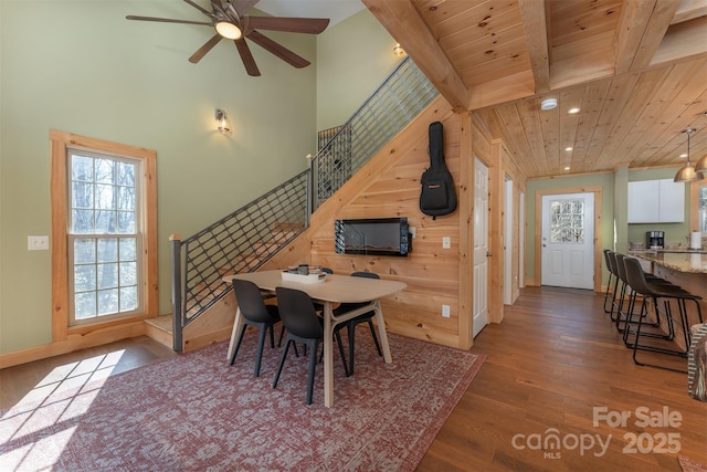 dining area with wood ceiling, ceiling fan, dark hardwood / wood-style floors, beamed ceiling, and a towering ceiling