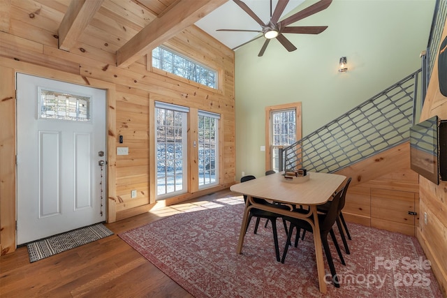 dining area with hardwood / wood-style flooring, ceiling fan, wooden walls, high vaulted ceiling, and beamed ceiling