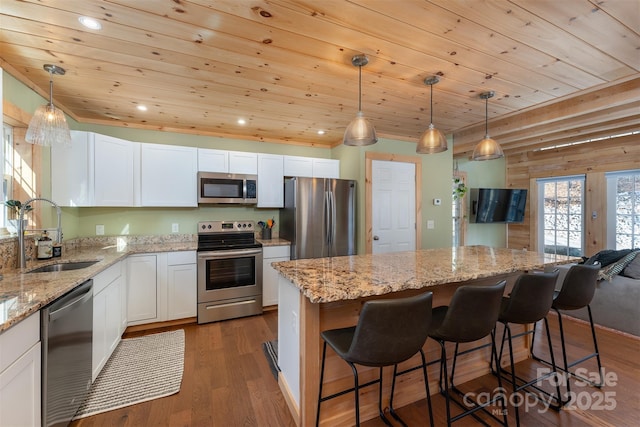 kitchen with pendant lighting, sink, stainless steel appliances, and a kitchen island