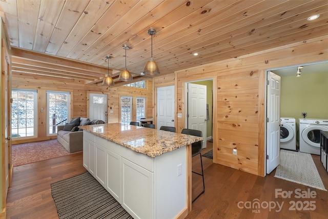 kitchen featuring white cabinetry, separate washer and dryer, hanging light fixtures, dark hardwood / wood-style flooring, and light stone countertops