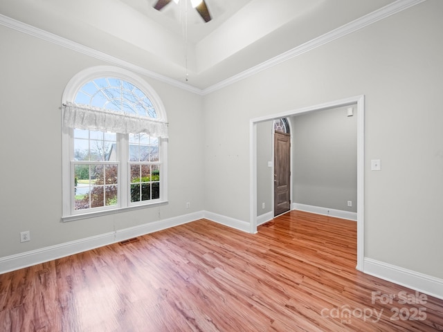 spare room with a tray ceiling, ornamental molding, light hardwood / wood-style floors, and ceiling fan