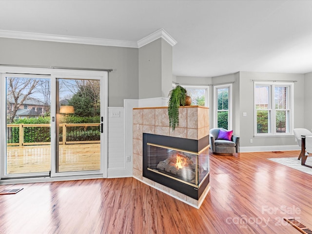 unfurnished living room with a tiled fireplace, hardwood / wood-style flooring, and ornamental molding